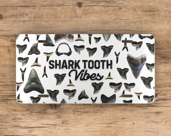 May include: White license plate with a black and white pattern of shark teeth and the text "SHARK TOOTH Vibes".