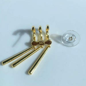 May include: Gold-toned earring with three dangling bars and a triple hoop design. The earring has a marking that reads "5925".