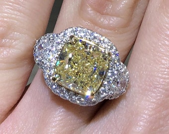 May include: A yellow cushion-cut diamond engagement ring with a halo setting and a double row of smaller diamonds on the band.