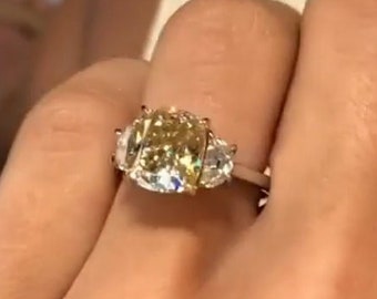May include: A gold ring with a large, cushion-cut yellow diamond and two smaller, triangular diamonds on either side.