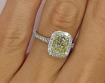 May include: A yellow diamond engagement ring with a halo setting. The ring is on a person's finger.