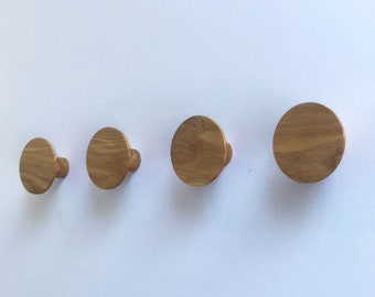 May include: Four wooden wall hooks in a row, each with a round, flat top and a small, cylindrical base.