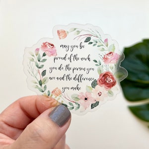 May include: A clear sticker with a watercolor floral wreath and the text "may you be proud of the work you do. the person you are and the difference you make."