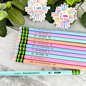 Puede incluir: Un conjunto de l&aacute;pices de colores pastel con frases motivadoras como "Soy valiente" y "Soy creativo". Tambi&eacute;n se ven dos pegatinas con forma de flor con afirmaciones positivas. Un l&aacute;piz Dixon Ticonderoga tambi&eacute;n est&aacute; en la imagen.
