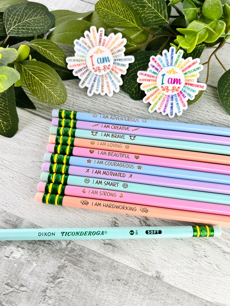 Puede incluir: Un conjunto de l&aacute;pices de colores pastel con frases motivadoras como "Soy valiente" y "Soy creativo". Tambi&eacute;n se ven dos pegatinas con forma de flor con afirmaciones positivas. Un l&aacute;piz Dixon Ticonderoga tambi&eacute;n est&aacute; en la imagen.
