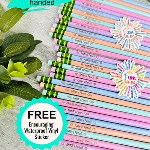 May include: A collection of pastel-colored pencils with green erasers, each labeled "ANNA's Pencil" with various small icons. Two stickers with positive affirmations are also visible. The image includes the text "Left or Right handed" and "FREE Encouraging Waterproof Vinyl Sticker."