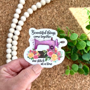 May include: A purple sewing machine with a floral design and the text "Beautiful things come together one stitch at a time".