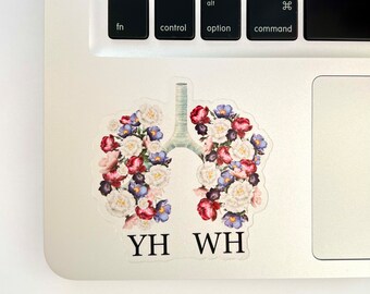 May include: A sticker of a stylized human lung with flowers in shades of pink, white, and blue. The text "YH WH" is below the lung.