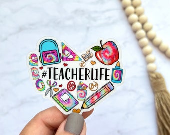 May include: A heart-shaped sticker with a tie-dye design featuring school supplies and the text "#TEACHERLIFE".
