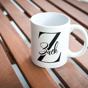 May include: White ceramic mug with a black letter Z and the name "Zack" written in a cursive font.