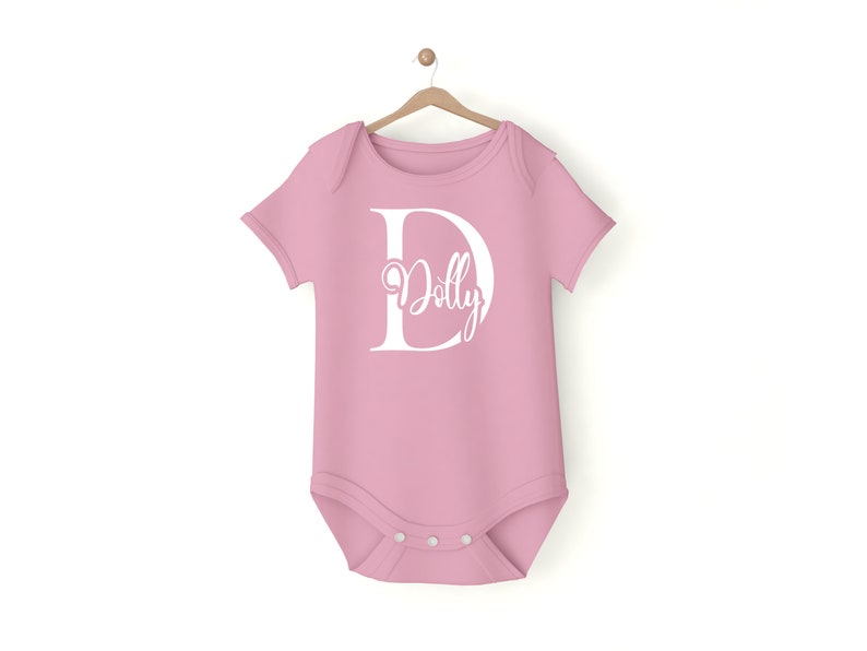 May include: A pink baby onesie with a white letter D and the name "Dolly" inside the letter.