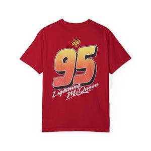 Pu&ograve; includere: Maglietta rossa con un grande numero 95 giallo e arancione sul retro. Il testo "Lightning McQueen" &egrave; scritto in bianco sotto il numero.