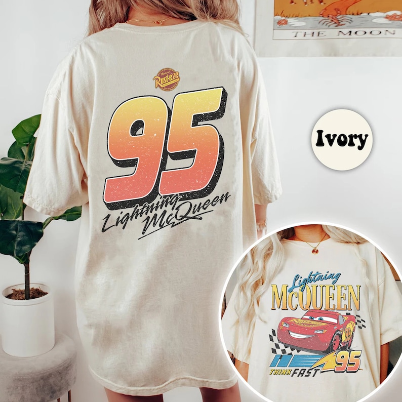 Pu&ograve; includere: Maglietta oversize color avorio con una grafica del numero di auto da corsa di Saetta McQueen 95 sul retro. La parte anteriore della maglietta presenta una grafica pi&ugrave; piccola dell'auto da corsa di Saetta McQueen con il testo "Lightning McQueen" e "Think Fast" in basso.