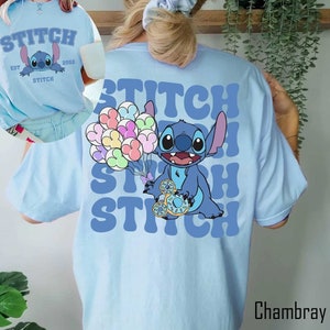 May include: Light blue t-shirt with a cartoon Stitch holding balloons and the text "Stitch" repeated in a retro font.