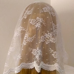 May include: White lace veil with a scalloped edge. The veil is made of delicate lace and is perfect for a special occasion.