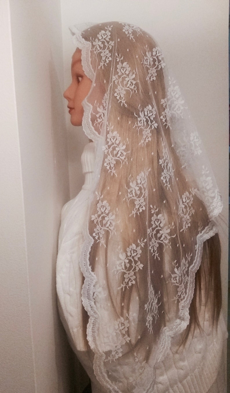 May include: White lace veil with floral pattern. The veil is sheer and has a scalloped edge.