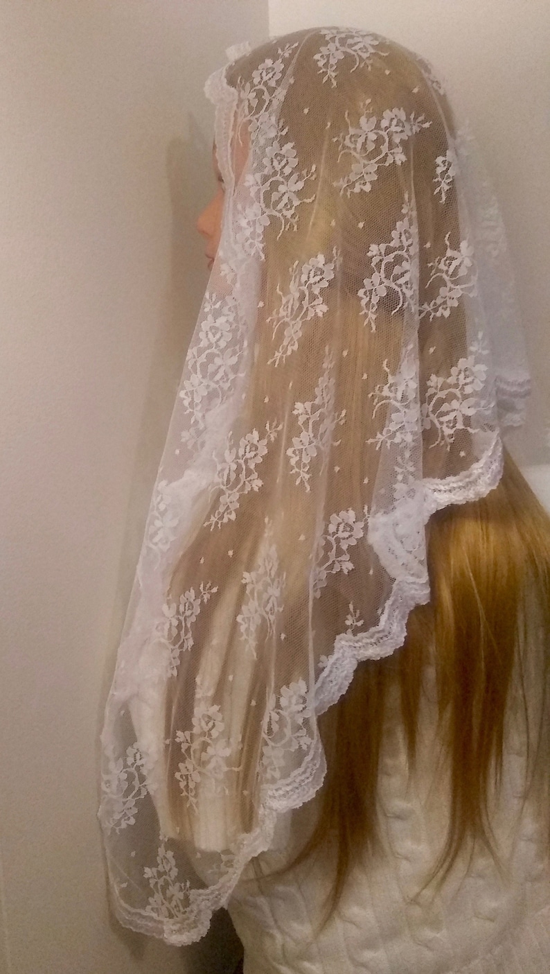 May include: White lace veil with floral pattern. The veil is sheer and has a scalloped edge.
