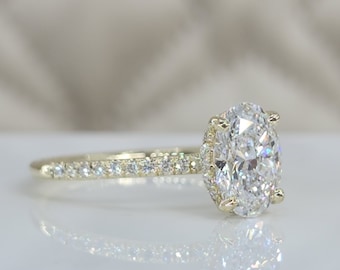 May include: A gold engagement ring with a large oval-shaped diamond center stone and a band of smaller diamonds.