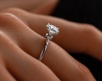 May include: A silver engagement ring with a large, round, clear diamond center stone and smaller diamonds on the band.