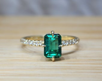 May include: A gold ring with a large emerald green gemstone surrounded by smaller diamonds.