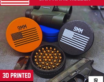 May include: An orange and black 9mm ammo holder with an American flag design. The image also shows a black handgun, a container of bullets, and the text "3D PRINTED MADE IN USA".