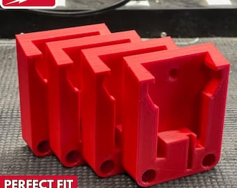 May include: Three red 3D printed battery holders for Milwaukee M18 batteries.  The holders are designed to fit snugly around the batteries and have a perfect fit.  The text "PERFECT FIT 3D PRINTED!" is printed below the holders.