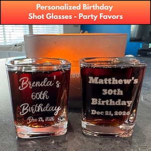 May include: Two square shot glasses filled with a dark liquid. One glass is engraved with "Brenda's 60th Birthday Dec 21, 2026". The other glass is engraved with "Matthew's 30th Birthday Dec 21, 2026". The text "Personalized Birthday Shot Glasses - Party Favors" is at the top.
