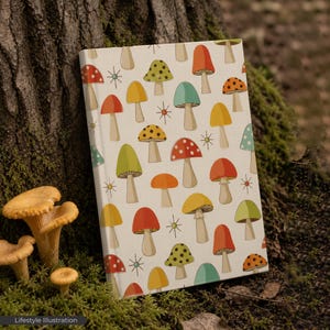May include: A notebook with a cream-colored cover featuring a pattern of colorful mushrooms in red, yellow, green, and orange. The notebook is propped against a tree trunk, with mushrooms in the foreground. The text "Lifestyle Illustration" is at the bottom.