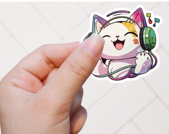 May include: A sticker of a cartoon cat wearing headphones and listening to music. The cat is white with pink and yellow markings. The headphones are green and have a rainbow cord. The sticker is on a white tiled background.