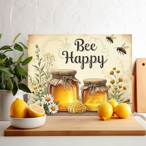 Könnte beinhalten: Dekorativer Druck mit dem Schriftzug „Bee Happy“ mit zwei Honiggläsern, einer Honigwabe und Zitronen. Der Druck hat eine Vintage-Ästhetik mit Bienen und floralen Akzenten. Die Gläser sind mit goldenem Honig gefüllt.