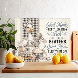 May include: A rectangular cutting board featuring a white goose wearing a checkered apron and bow, holding an electric mixer. The text reads: Good Moms LET THEIR KIDS Lick THE BEATERS. Great Moms TURN THEM OFF. Includes illustrations of a mixing bowl, flour, and baking tools.