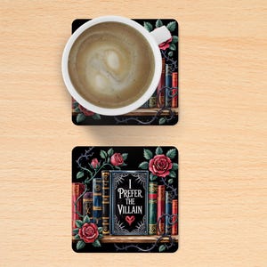 Puede incluir: Dos posavasos cuadrados negros con fondo oscuro. El posavasos superior presenta una taza de caf&eacute; blanca con un l&iacute;quido marr&oacute;n en su interior. El posavasos inferior presenta una estanter&iacute;a con libros y rosas. Los libros tienen una gama de colores rojo, dorado y negro. El texto del libro dice "I Prefer the Villain".