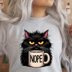 May include: A gray sweatshirt with a black cat holding a white coffee mug that says "NOPE".