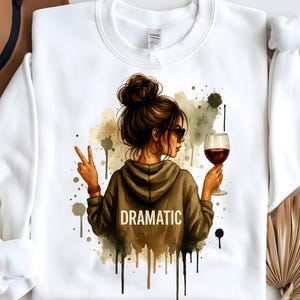 May include: White sweatshirt with a watercolor illustration of a woman with a glass of red wine and the word "DRAMATIC" printed on the front.