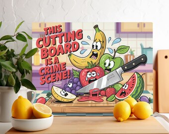 May include: A colorful cutting board with a cartoon banana, watermelon, strawberry, apple, and grapes. The text "This Cutting Board Is A Crime Scene!" is written in red and white letters on the board.