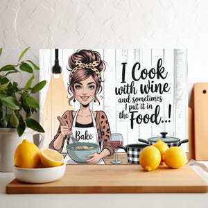 May include: A decorative kitchen sign featuring a cartoon woman with a whisk, mixing in a bowl. The sign reads "I Cook with wine and sometimes I put it in the Food...!". A glass of wine, lemons, and pots are also shown.