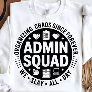 May include: White sweatshirt with a black circle graphic that says "Organizing Chaos Since Forever Admin Squad We Slay All Day". The graphic also includes hearts, a checklist, and office supplies.