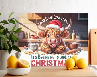 May include: A canvas print featuring a cartoon Highland cow wearing a Santa hat, surrounded by baking supplies. Text reads "Sugar, Flour, Exhaustion..." and "It's Beginning to Look a Lot Like Christmas". Lemons in a white bowl are in the foreground.