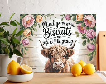 Könnte beinhalten: Ein rustikales Holzschild mit einem Hochlandrind und floralen Akzenten. Das Schild lautet "Mind your own Biscuits and life will be gravy."