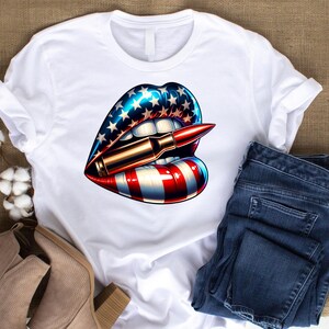 Pode incluir: Camiseta branca com um design de lábios vermelho, branco e azul. Os lábios estão segurando uma bala entre os dentes.