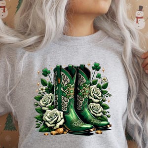 May include: A grey sweatshirt featuring a green, white and gold design of two cowboy boots with shamrocks and flowers.
