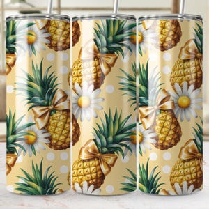 Pode incluir: Um conjunto de três copos de aço inoxidável com um padrão repetido de abacaxis, margaridas e laços em um fundo amarelo. Os copos têm uma palha e medem aproximadamente 20 cm de altura.