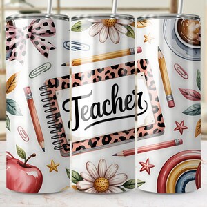 Könnte beinhalten: Ein weißer Becher mit Lehrer-Motiv, mit einem Notizbuch mit dem Wort "Teacher", Bleistiften, Blumen und einem Regenbogen. Das Design umfasst eine Schleife, einen Apfel und eine Kaffeetasse. Der Becher hat einen Strohhalm.
