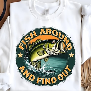 May include: White sweatshirt with a green, orange, and blue graphic of a fish jumping out of the water. The graphic says "Fish Around And Find Out".