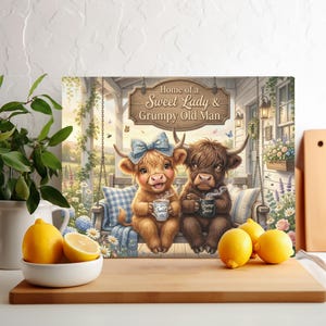 May include: A rectangular glass cutting board featuring an illustration of two Highland cows sitting on a porch swing. The text reads Home of a Sweet Lady & Grumpy Old Man. The cows hold mugs labelled Sweet and Grump Juice respectively.