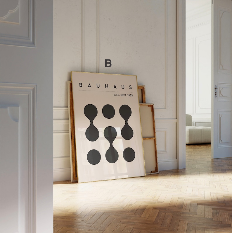 Puede incluir: Un p&oacute;ster enmarcado con el texto "BAUHAUS" y "JULI - SEPT 1923" en texto negro sobre fondo blanco. El p&oacute;ster presenta un dise&ntilde;o de seis formas abstractas negras.