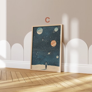 May include: A framed print of a starry night sky with a small figure standing on a white surface, looking up at the planets. The planets are in various shades of blue, orange, and white.