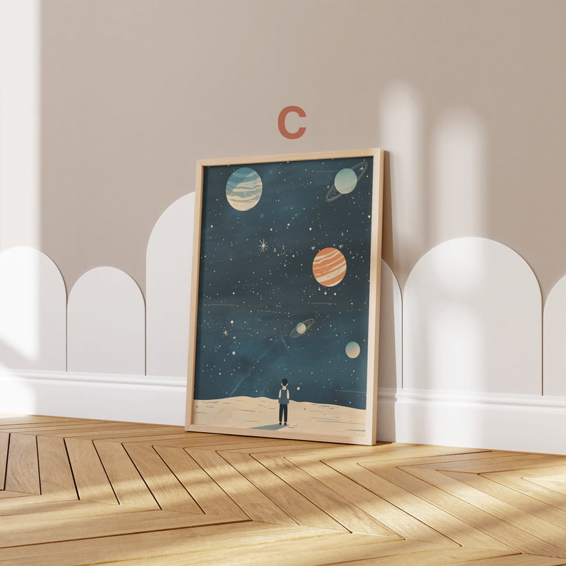 May include: A framed print of a starry night sky with a small figure standing on a white surface, looking up at the planets. The planets are in various shades of blue, orange, and white.