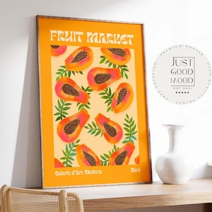 Könnte beinhalten: Orange gerahmter Kunstdruck mit Papaya-Design. Der Druck zeigt oben die Worte "FRUIT MARKET" und unten "Galerie d'Art Modern". Die Papaya-Scheiben sind rosa und orange mit dunkelbraunen Samen, umgeben von grünen Blättern.