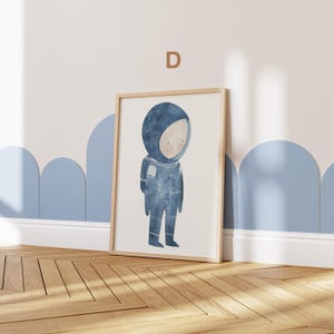 May include: A framed illustration of a child dressed as an astronaut with a blue and white spacesuit. The background is white with a light blue border.